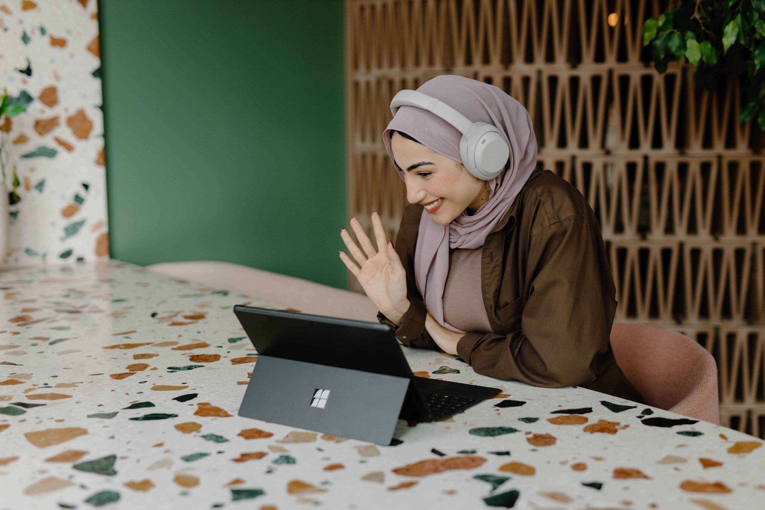 A woman smiling and waving at her laptop camera