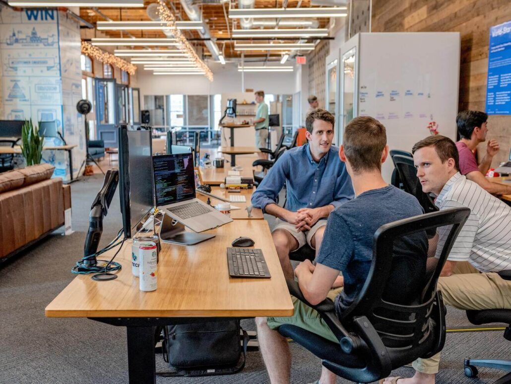 a group of men sitting sitting in an office, tallking.