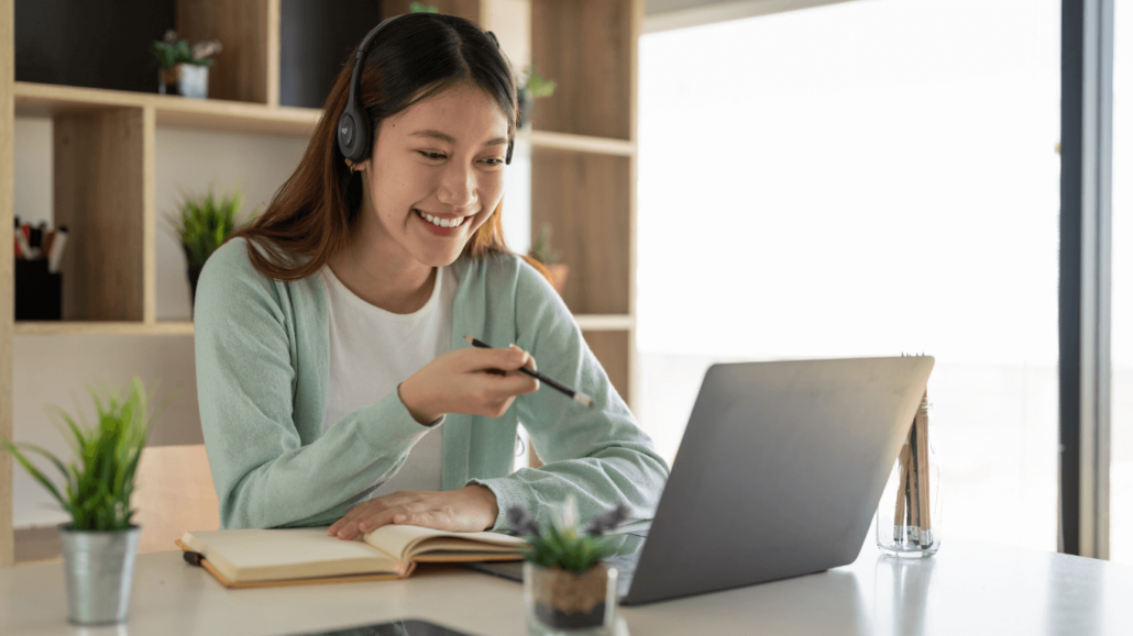 a woman smiling while looking at a laptop.