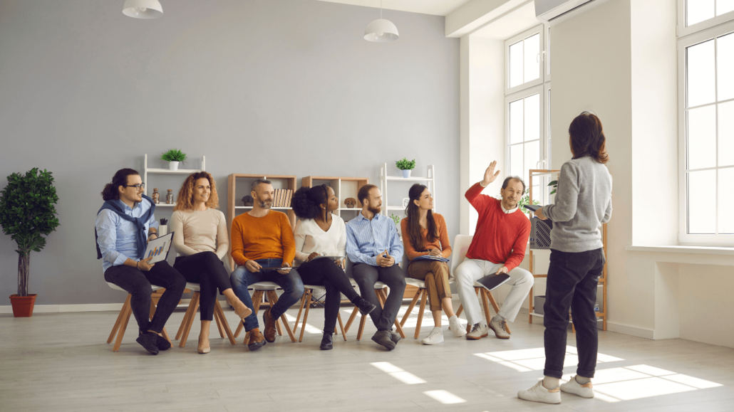 diverse group of people sitting while a woman is speaking to them