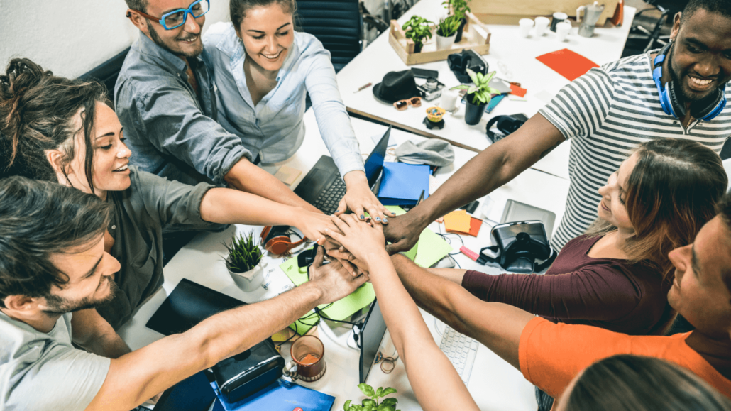 employees in a circle, stacking their hands in the middle