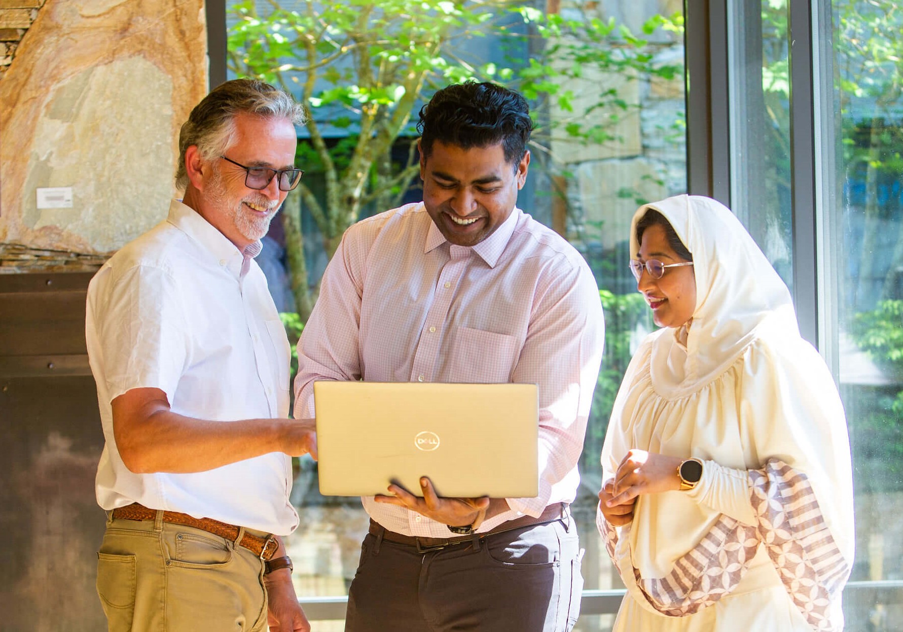 employees looking at laptop and smiling